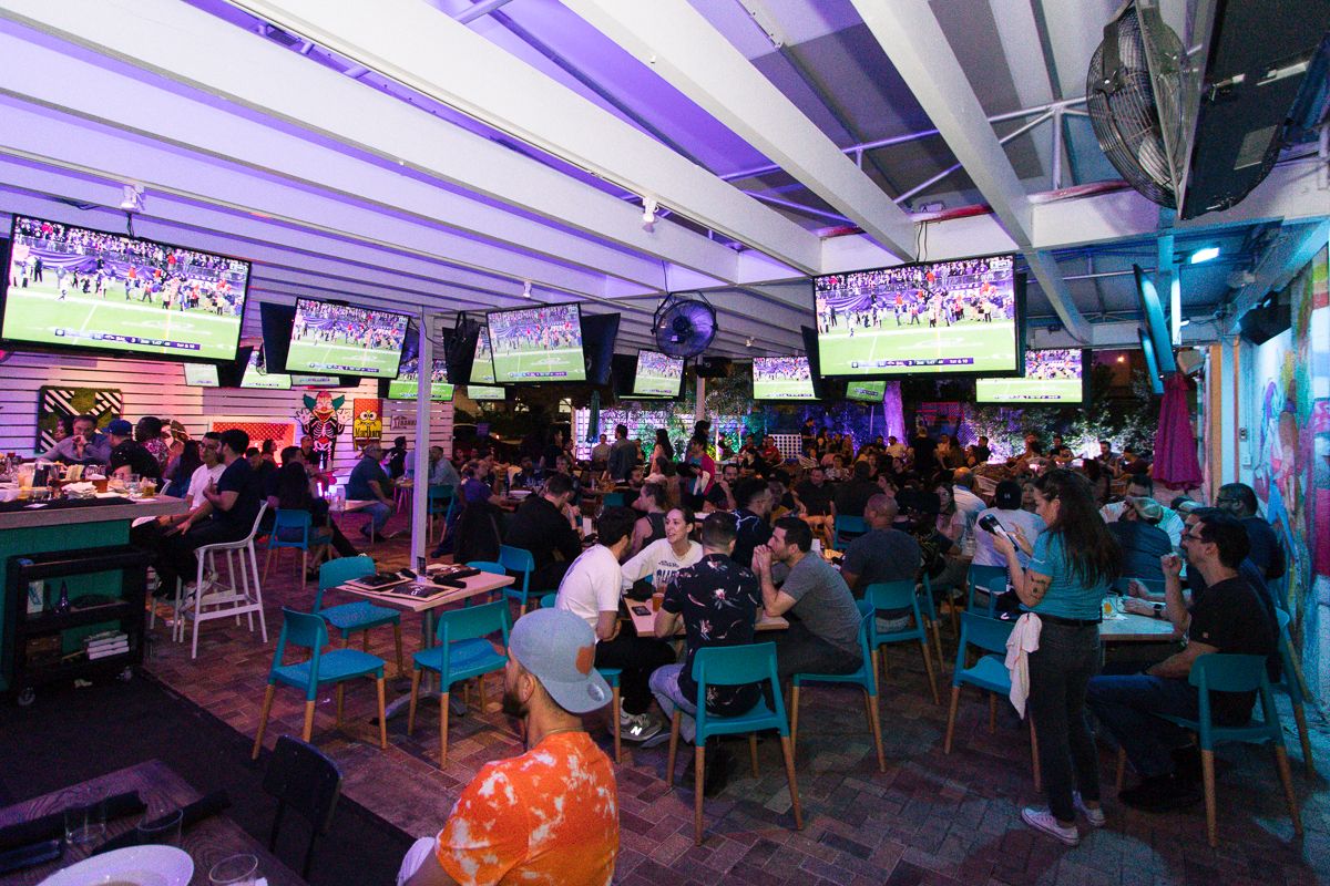 Packed covered patio at Grails Miami with college football on a wall of overhead TVs, where FSU fans watch the Florida State Seminoles in Miami