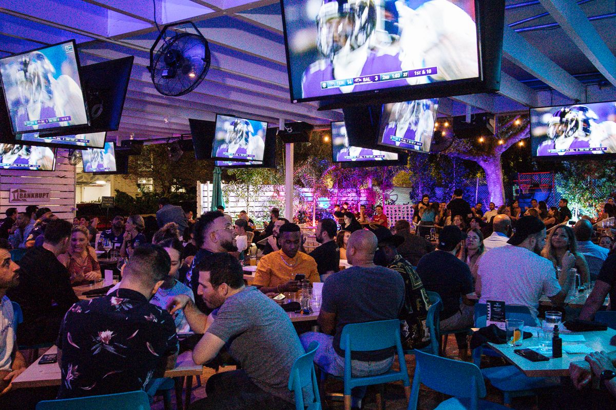 Packed NFL watch party crowd under the covered patio at Grails Miami with football on every screen, the Philadelphia Eagles bar in Wynwood