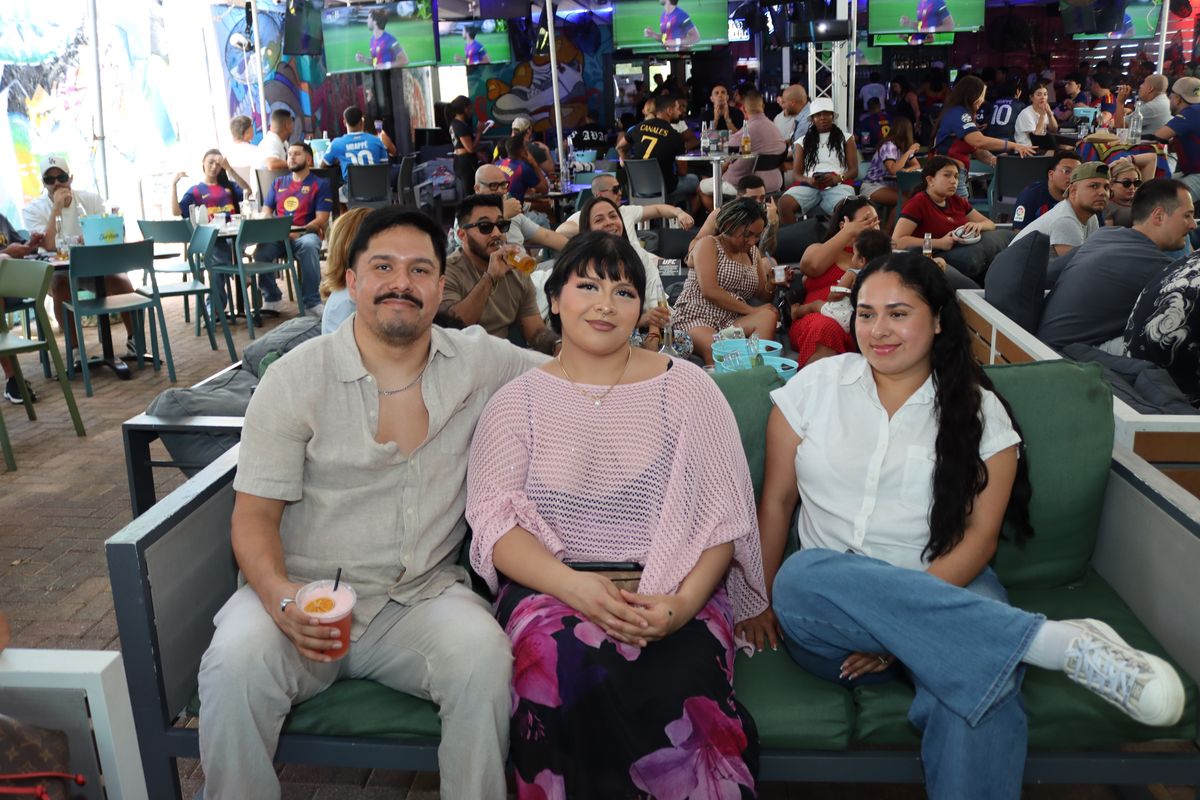 Three friends posing on a green patio couch during a Premier League watch party at Grails Wynwood