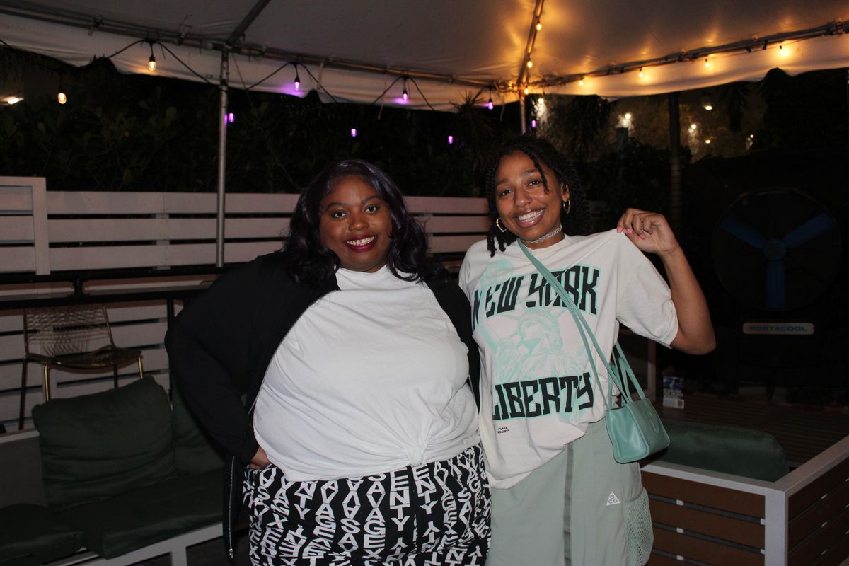 Two women on the Grails Wynwood patio at night during a WNBA watch party, Miami's WNBA sports bar