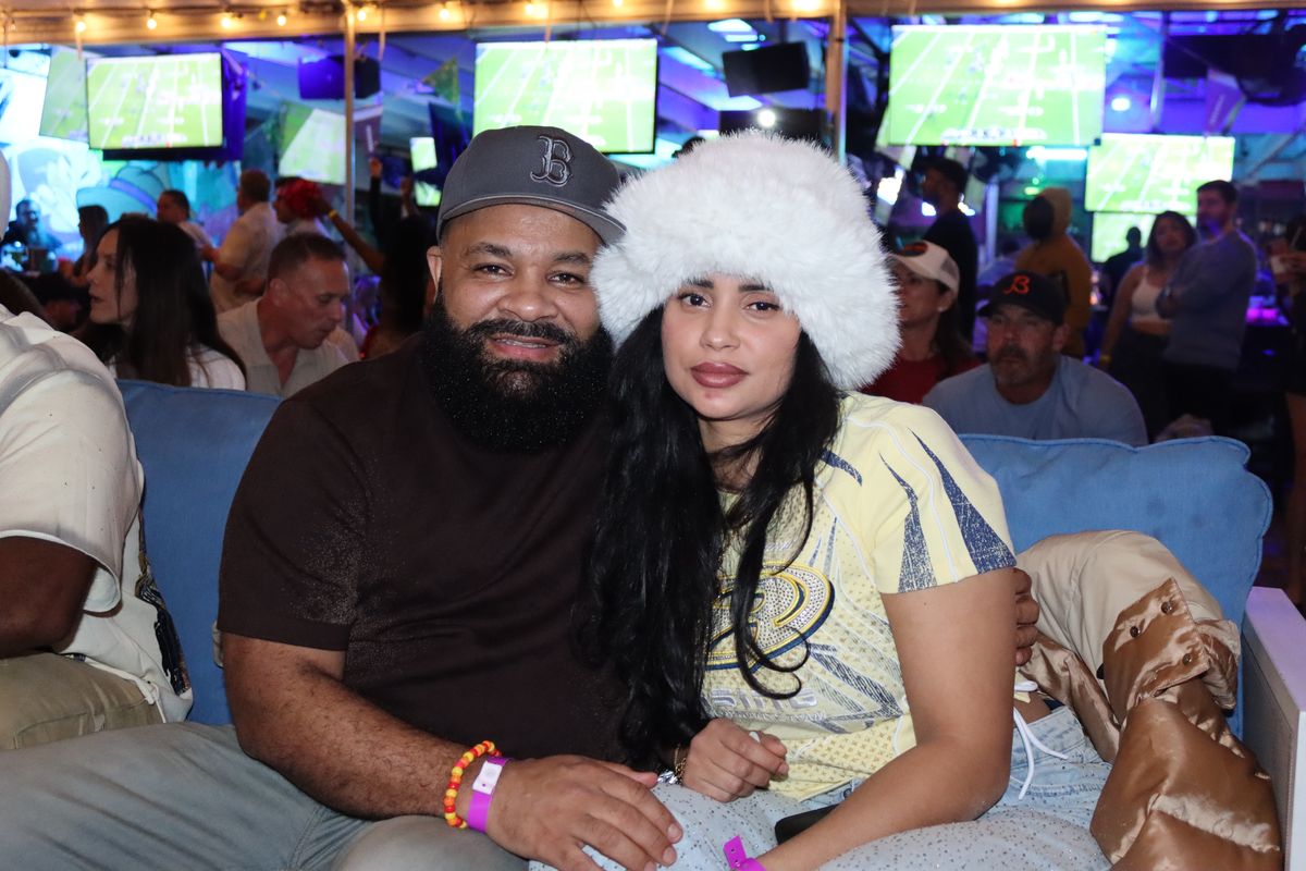 Couple settled into the lounge couch with the NFL game on the screens behind them at Grails Miami in Wynwood