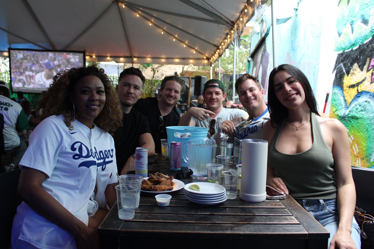 Dodgers fans gathered around a Grails Wynwood patio table watching the MLB game during a World Series watch party