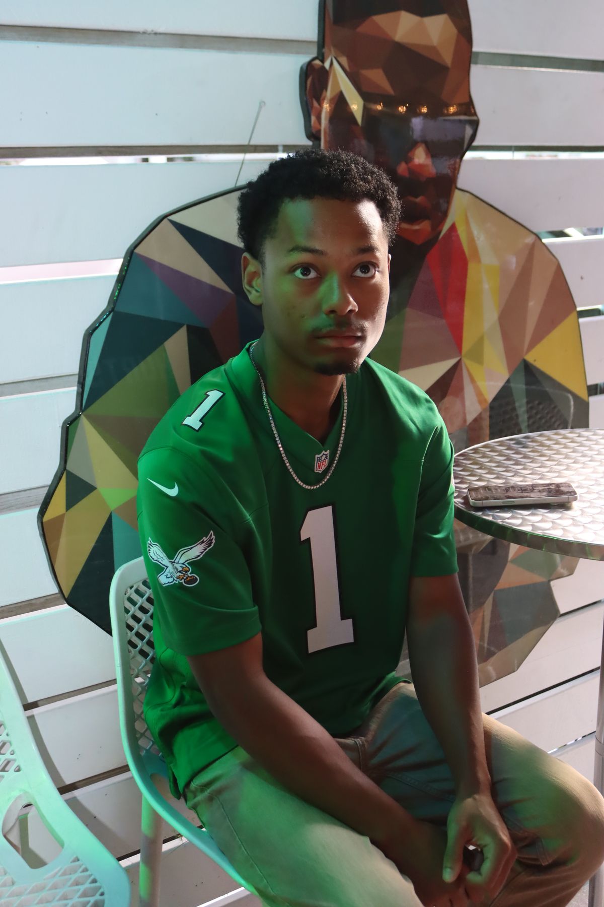 Fan in a kelly green Philadelphia Eagles number 1 jersey in front of the mural wall at Grails Miami in Wynwood