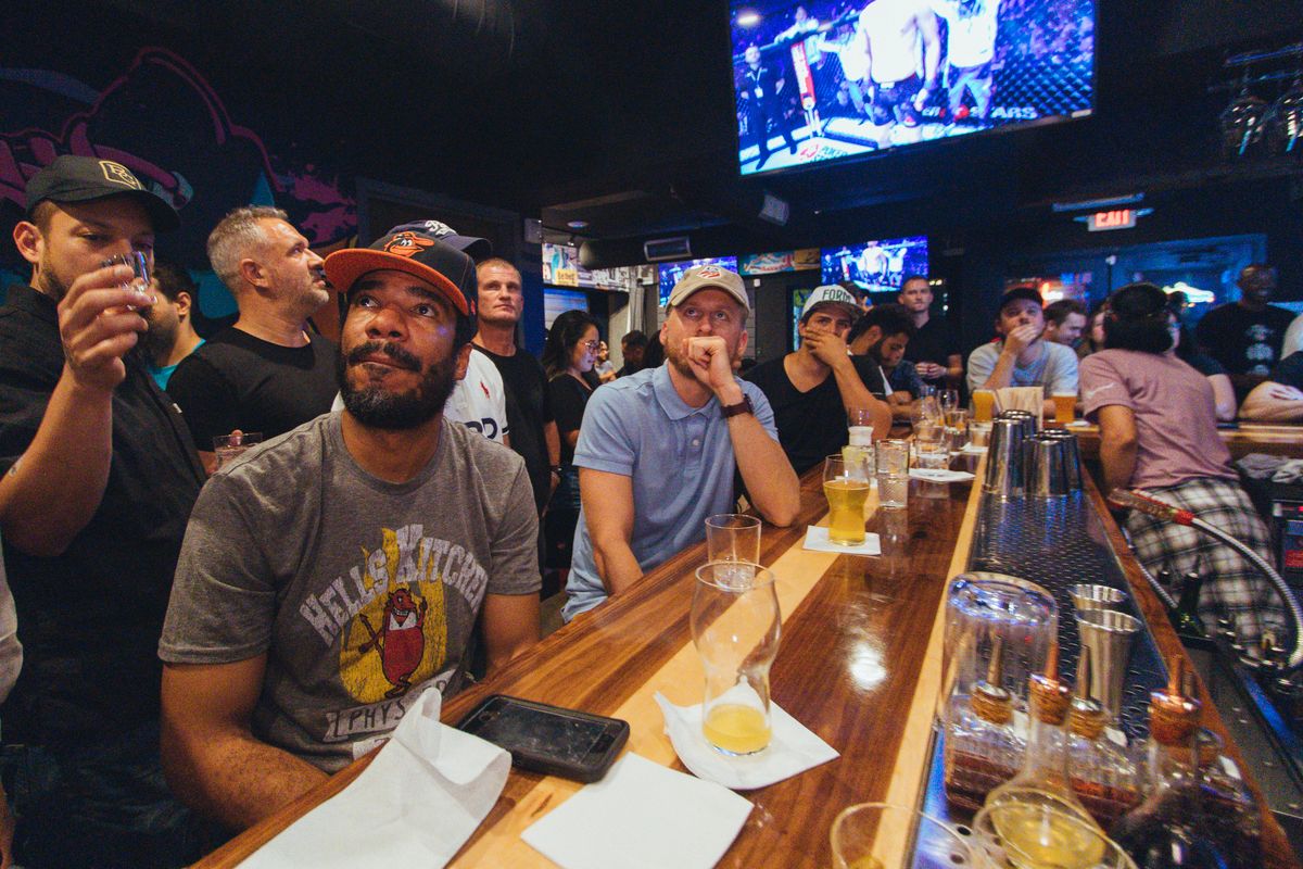 Fans lined up along the bar counter watching a fight on the overhead TVs at Grails Miami in Wynwood