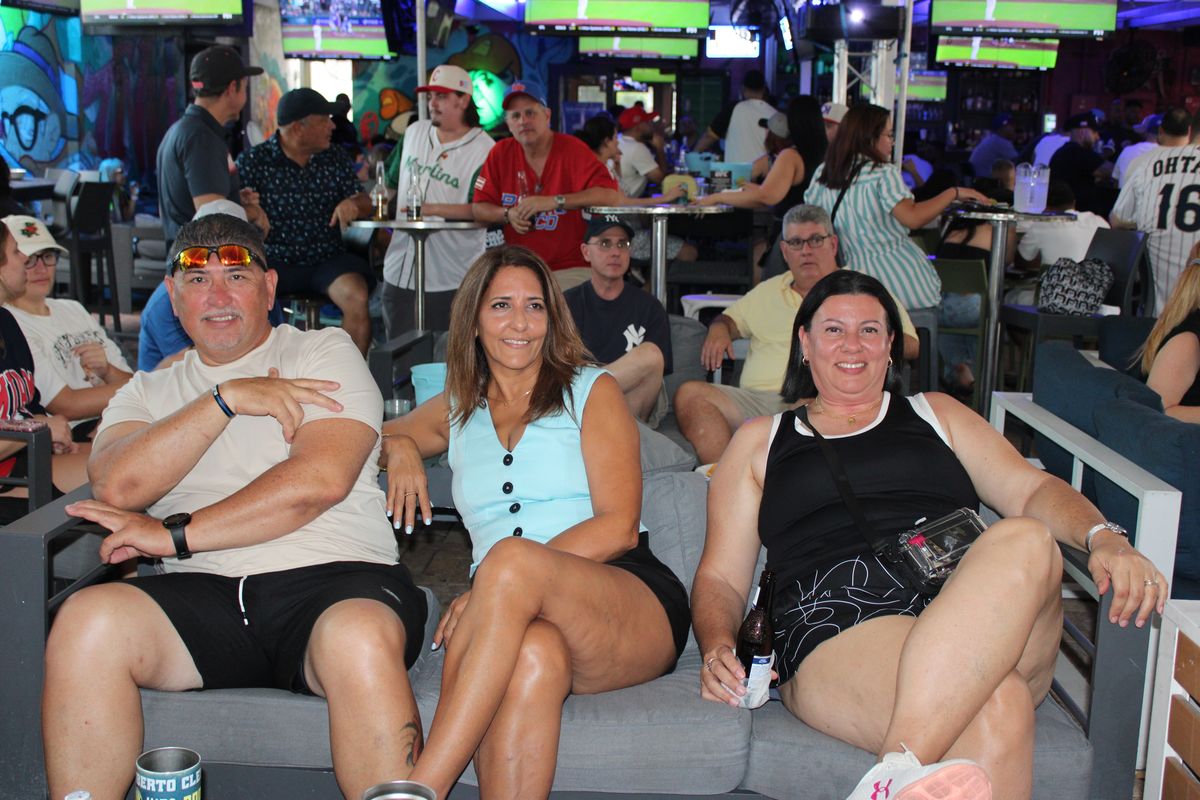 Three friends relaxing on a gray lounge couch at Grails Wynwood during a Miami Marlins baseball watch party