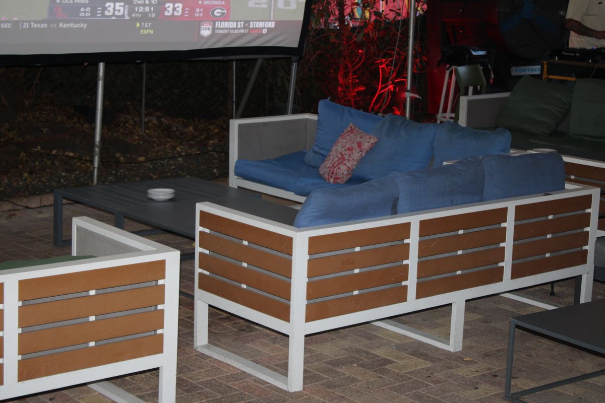Patio lounge couches at Grails Miami facing the big screen with a Florida State Seminoles game on it