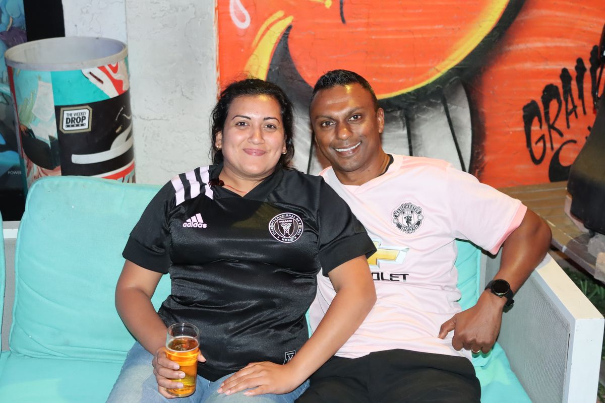 Couple wearing Inter Miami and Manchester United jerseys at the Grails Wynwood Premier League watch party in Miami