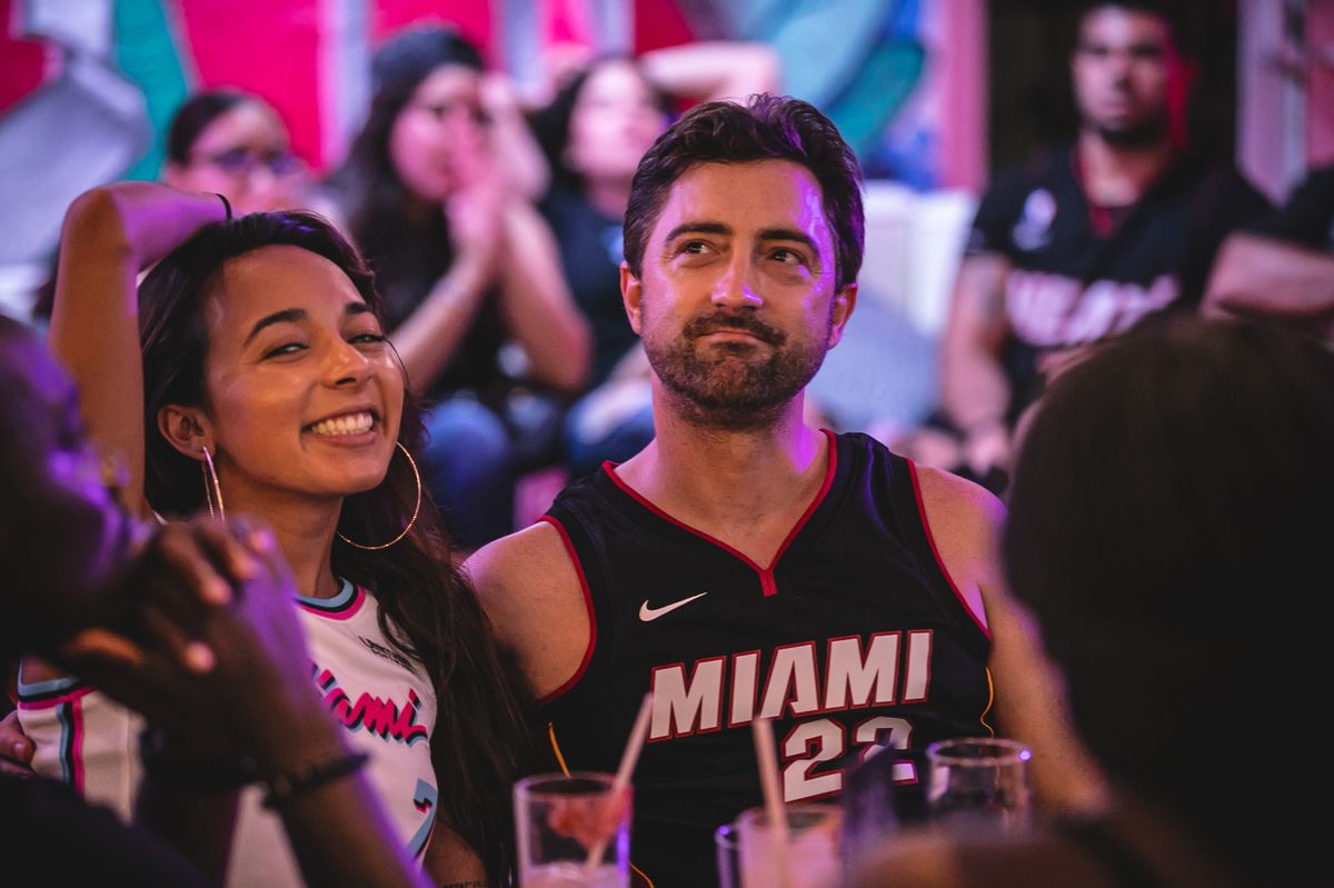 Couple in Miami Heat jerseys watching an NBA game at Grails Miami, the closest sports bar to Edgewater Miami