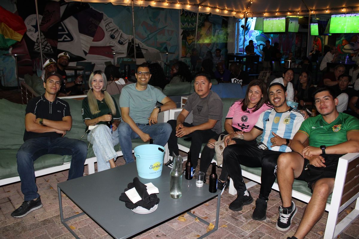 Group of seven friends in soccer jerseys posing on the Grails Wynwood patio couch during a Concacaf Gold Cup watch party