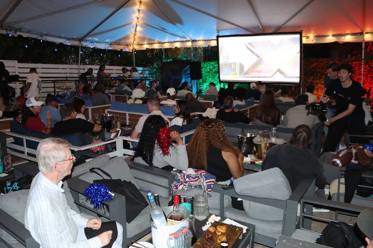 Crowd watching an NFL game on the giant projector screen under The Yard tent at Grails Miami, the Thursday Night Football sports bar in Miami