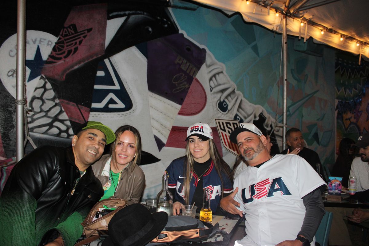 Group of four USA soccer fans posing at a Grails Wynwood table during a Concacaf Gold Cup watch party in Miami