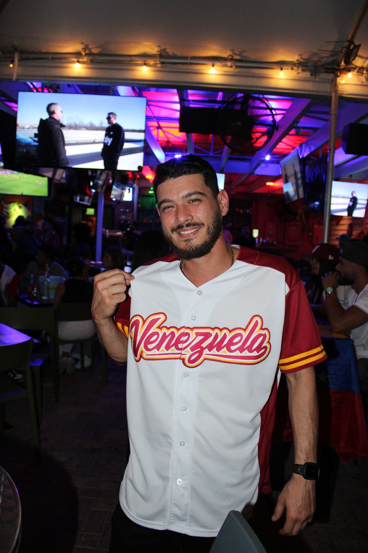 Smiling fan proudly displays his Venezuela baseball jersey at Grails Wynwood sports bar during a Miami Marlins game night