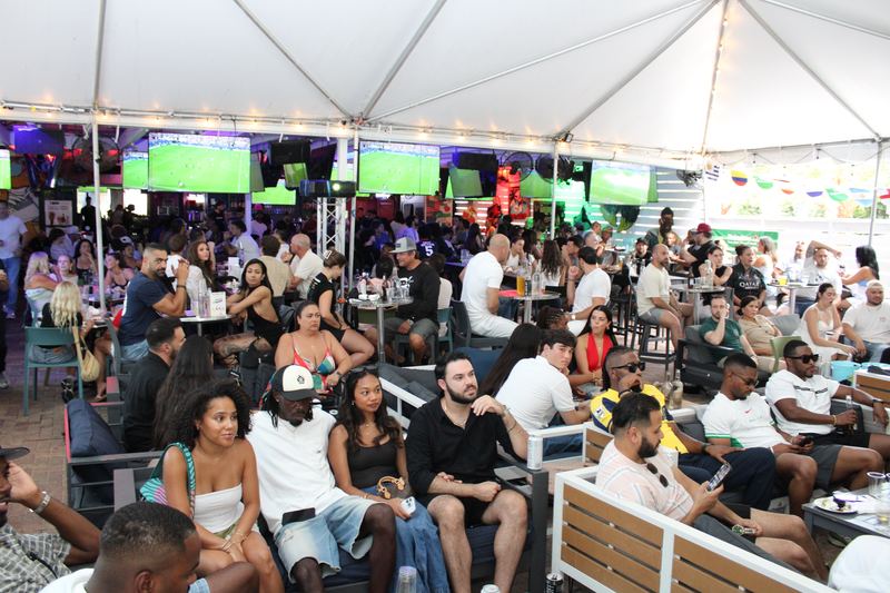 Full crowd watching soccer on the big screens under The Yard tent at Grails Miami during a marquee match