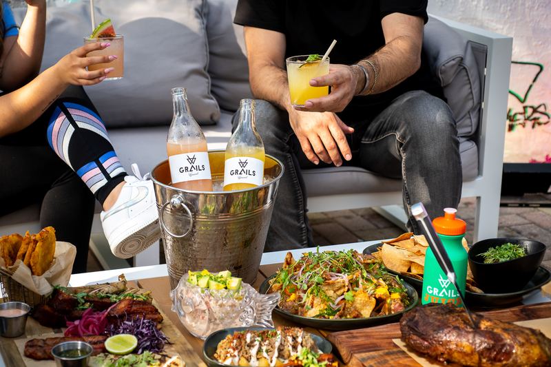 Shareable food and drink spread on a covered patio table at Grails Miami weekend brunch.