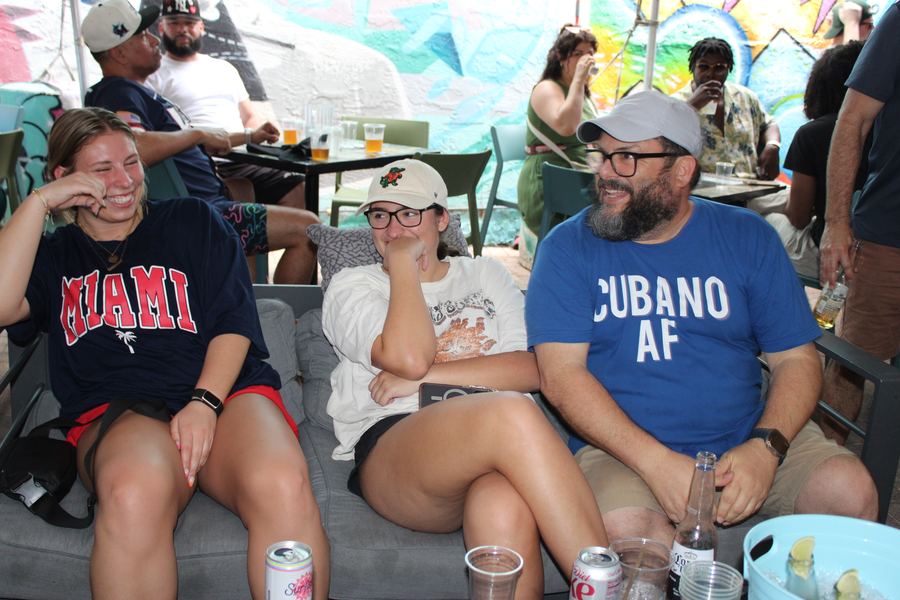 Friends laughing on a patio lounge couch during happy hour at Grails Miami in Wynwood