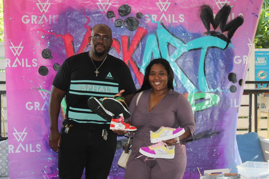 A couple holding up custom-painted sneakers at the Kick Art Workshop hosted at Grails Miami