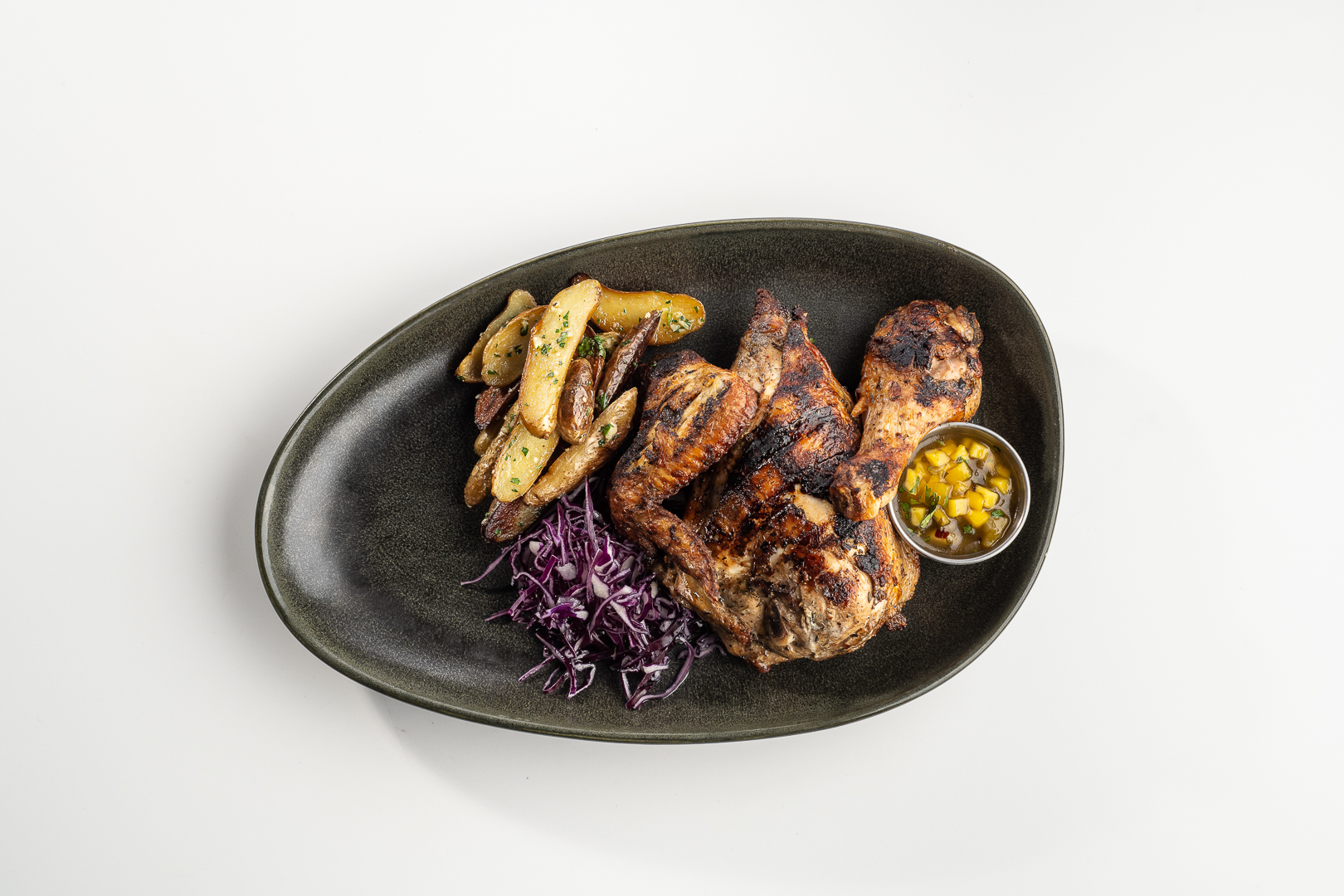 Overhead grilled chicken platter with potatoes, purple slaw, and mango salsa.