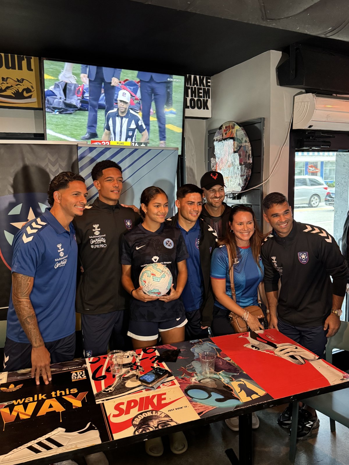 Puerto Rico national soccer team players pose with young fan holding soccer ball at Grails Miami meet-and-greet